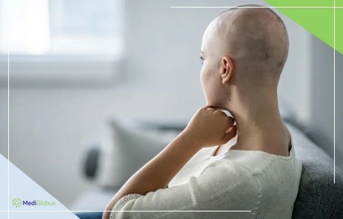 Побічні ефекти хімії жінка без волосся на голові сидить на дивані й дивиться у вікно