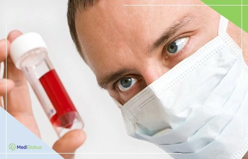 лечение лейкоза за границей мужчина в белой медицинской маске держит контейнер с красной жидкостью