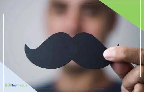 Movember — як долучитися до акції та підтримати обізнаність про чоловіче здоров’я чоловік тримає в руці чорні паперові вуса