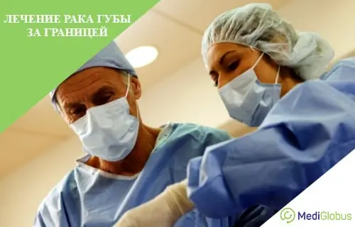 лечение рака губы два хирурга, мужчина и женщина, в стерильной одежде, перчатках и масках выполняют операцию