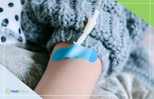рука пацієнта з внутрішньовенним катетером та системою для введення препаратів — проведення хіміотерапії