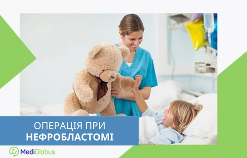 Операція при пухлині Вільмса Жінка в медичному одязі тримає іграшкового ведмедика і показує його дитині, яка лежить у лікарняному ліжку