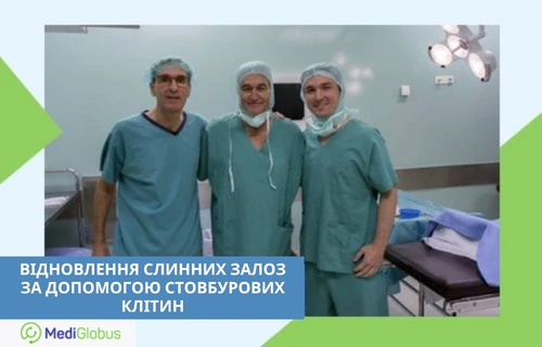 Відновлення слинних залоз за допомогою стовбурових клітин Троє лікарів в операційній, у хірургічному одязі та шапочках, позують на тлі операційного столу та медичного обладнання