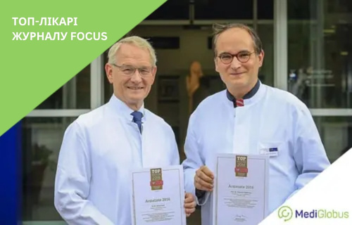 Кращі лікарі за версією журналу «Фокус» Двоє лікарів у білих халатах тримають сертифікати з логотипом журналу Focus, стоячи біля входу до клініки