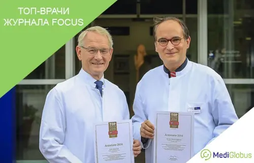 Топ-врачи журнала Фокус Два врача в белых халатах держат сертификаты с логотипом журнала Focus, стоя у входа в клинику