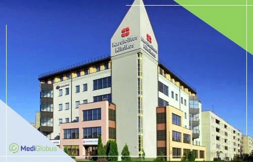 Ендопротезування кульшового суглоба в Литві — сучасна клініка Kardiolita Klinikos Сучасна клініка Kardiolita Klinikos у Литві з трикутним дахом і червоним логотипом