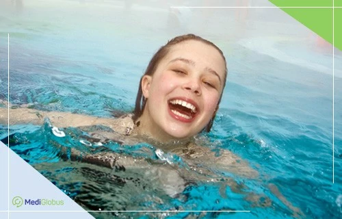 Курортне лікування в чеських лікарнях Усміхнена дівчина плаває в басейні
