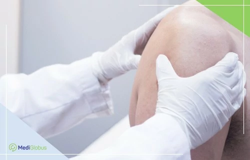 Переваги ендопротезування: консультація з ортопедом та підготовка до операції лікар оглядає плечовий суглоб пацієнта — діагностика перед ендопротезуванням