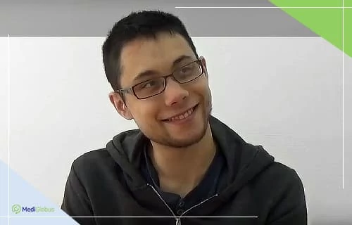 Відгук пацієнта про лікування діабету 1 типу стовбуровими клітинами Молодий чоловік в окулярах і темному одязі посміхається