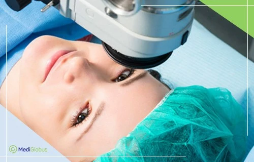 Пересадка рогівки в Ізраїлі Пацієнтка лежить під офтальмологічним мікроскопом під час обстеження або операції на оці; обличчя частково видно, голова вкрита хірургічною шапочкою, обладнання спрямовано на ділянку ока.