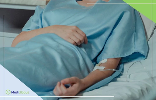Імунотерапія при раку печінки 4-ї стадії Пацієнт у світло-блакитному лікарняному халаті лежить на лікарняному ліжку з внутрішньовенним катетером (крапельницею) на передпліччі.