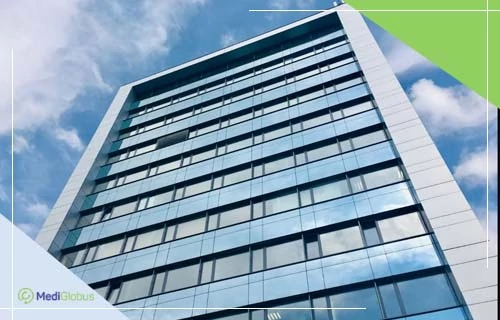 Лікування ретинопатії в Cellthera Stem Cell Therapy Center Висотна будівля з фасадом із блакитного дзеркального скла, що відбиває хмарне небо