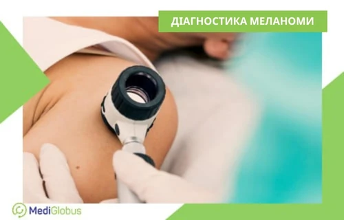 Лікар у рукавичках проводить огляд родимки на плечі пацієнта за допомогою збільшувального приладу