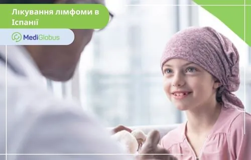 Шанси на одужання від лімфоми у дитини в Іспанії - понад 87% Лікар розмовляє з дівчинкою в хустці у лікарняній палаті